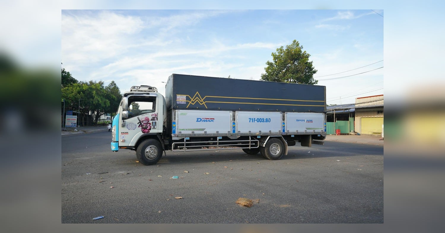 Bright delivery truck with colorful advertising wrap beside a highway billboard - Truck Wraps vs Billboard comparison