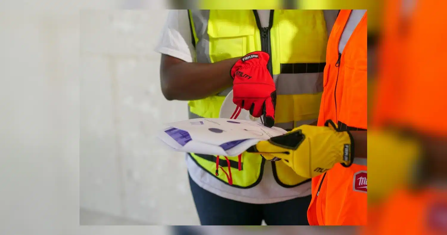 High-Visibility Safety Wear — Close-up of construction workers with safety gear reviewing printed documents.