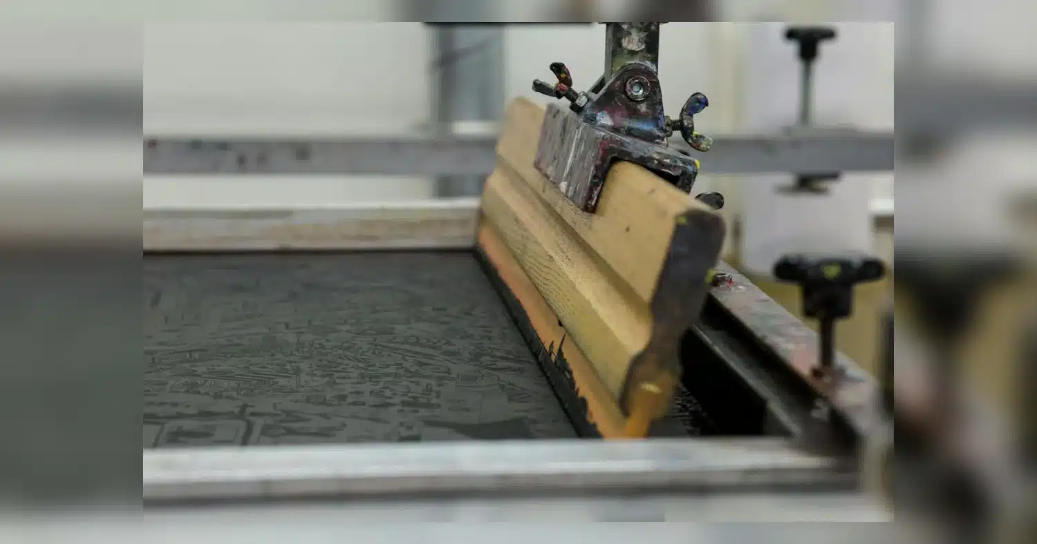 Custom T-Shirt Printing — Detailed view of a screen printing setup with a wooden squeegee in Luzern, Switzerland.