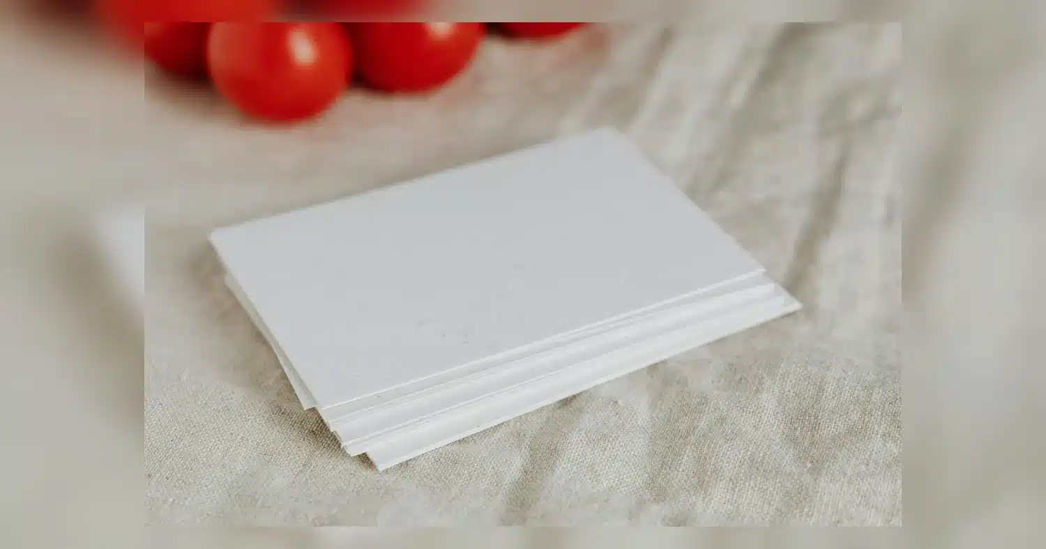 Paper Stocks — Stack of blank white cards on linen cloth with red tomatoes in background.