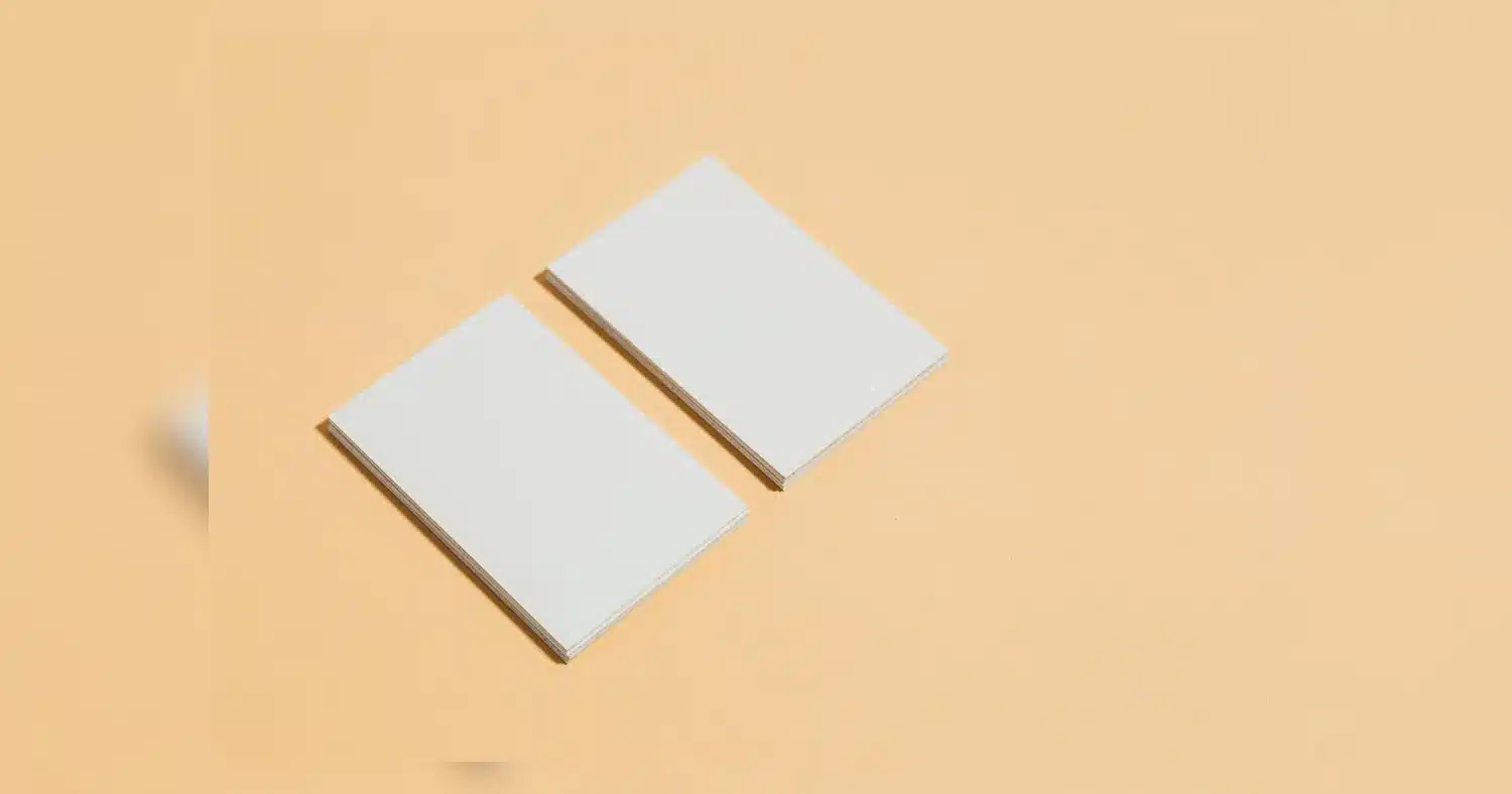 Business Cards Guide — Close-up of blank white business cards on a pastel orange background. Ideal for design mockups.