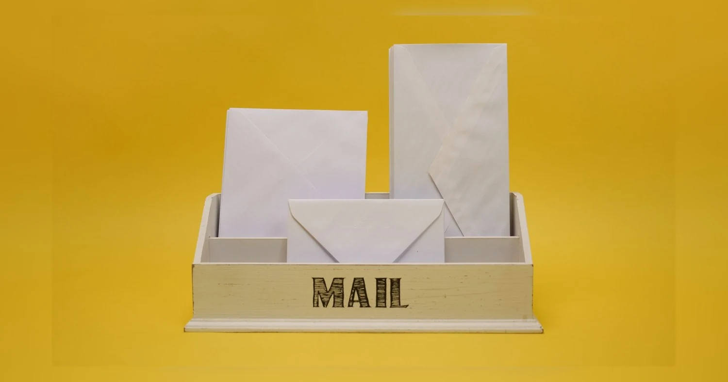 letterhead printing Toronto — White envelopes neatly arranged in a mail organizer against a vibrant yellow background.