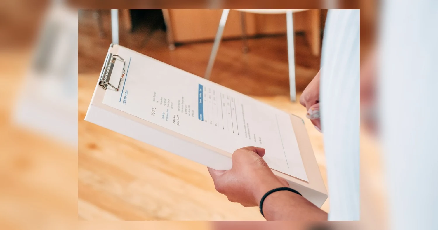 NCR forms — Close-up of hands holding a clipboard with business documents, indicating analysis and planning.