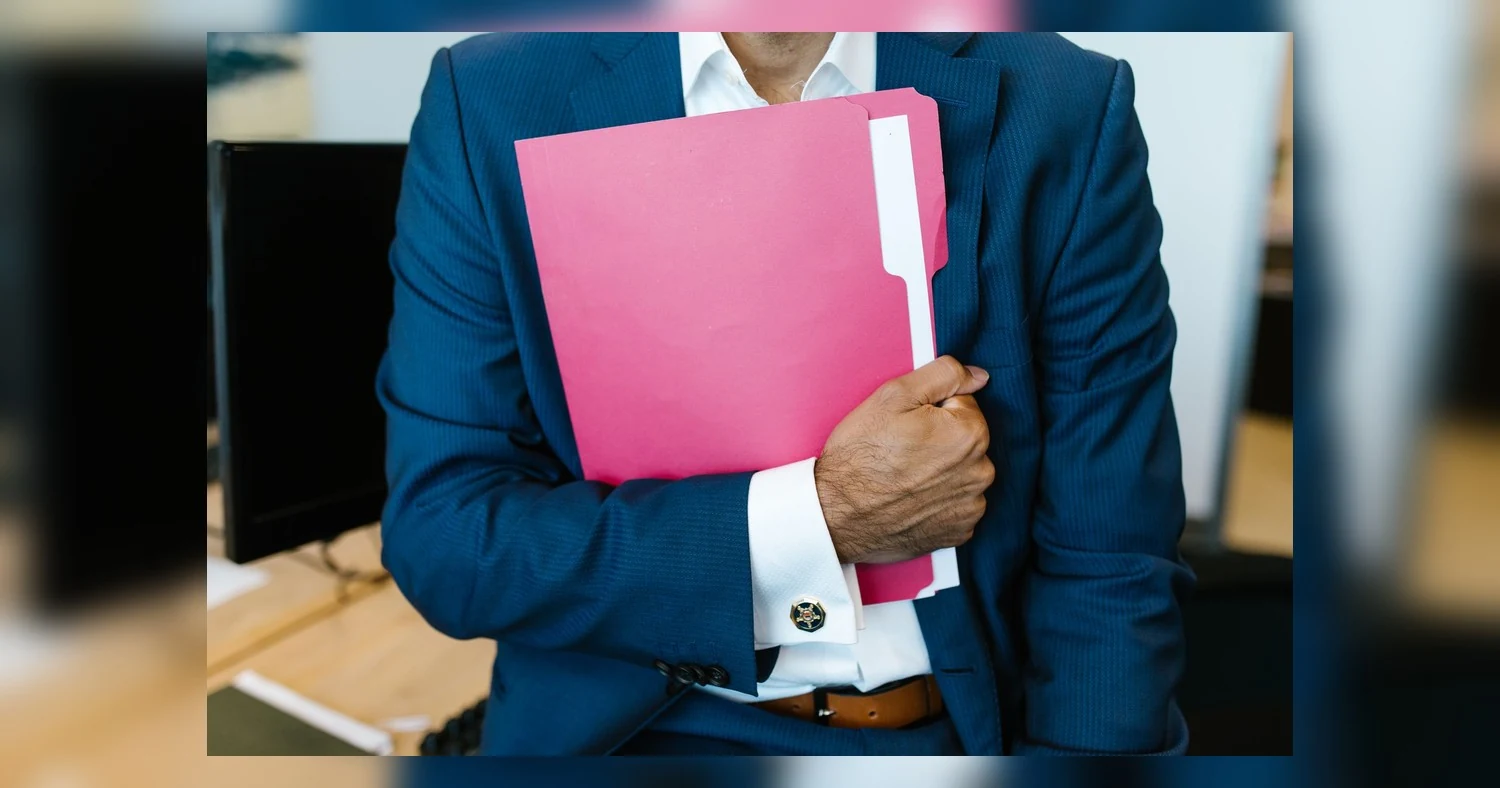 presentation folder printing — A professionally dressed man holding a pink folder in an office setting.