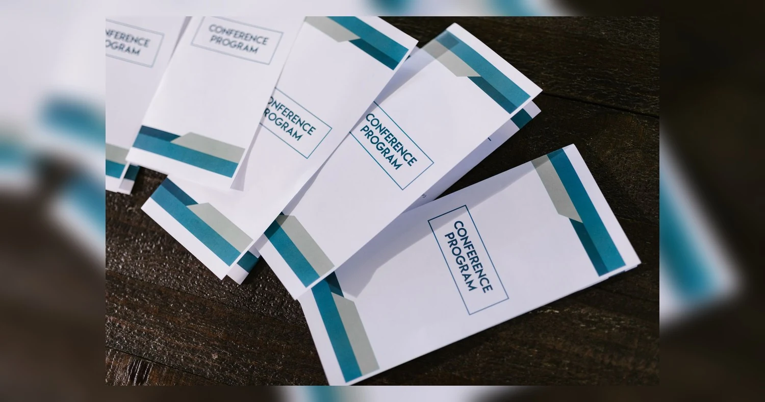 door hanger printing — Close-up of neatly arranged conference program pamphlets on a wooden surface, suitable for professiona