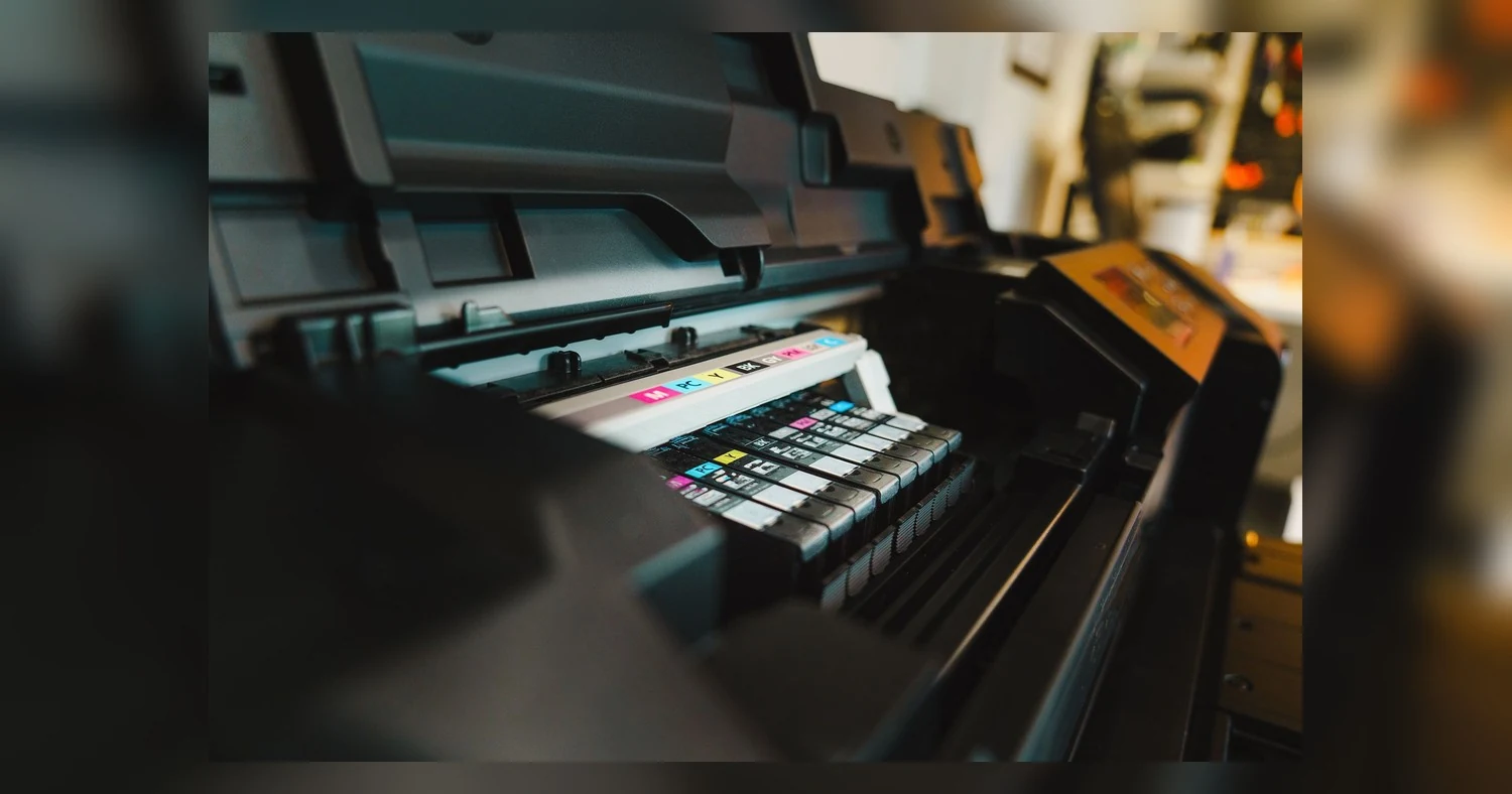 large format poster printing — Detailed view of ink cartridges inside a digital inkjet printer in an office setting.