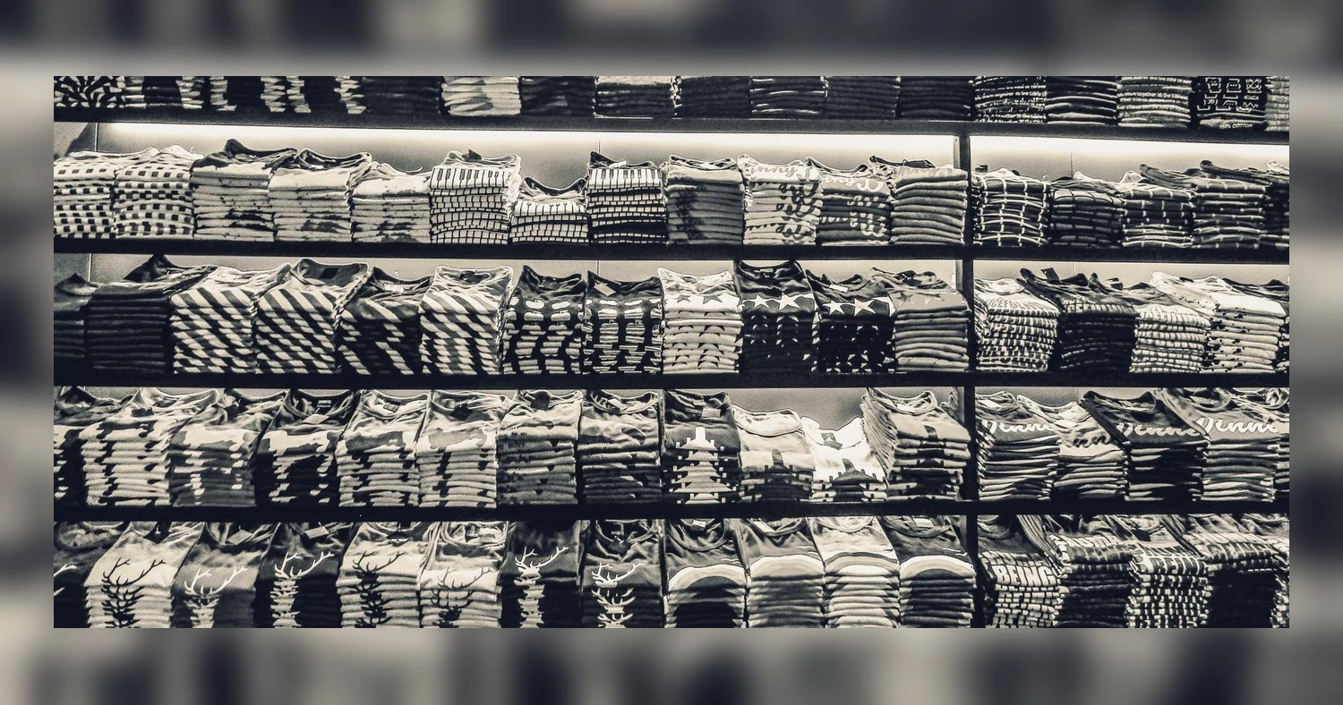 custom apparel for trade shows and event handouts — Black and white image showcasing neatly folded t-shirts stacked on store