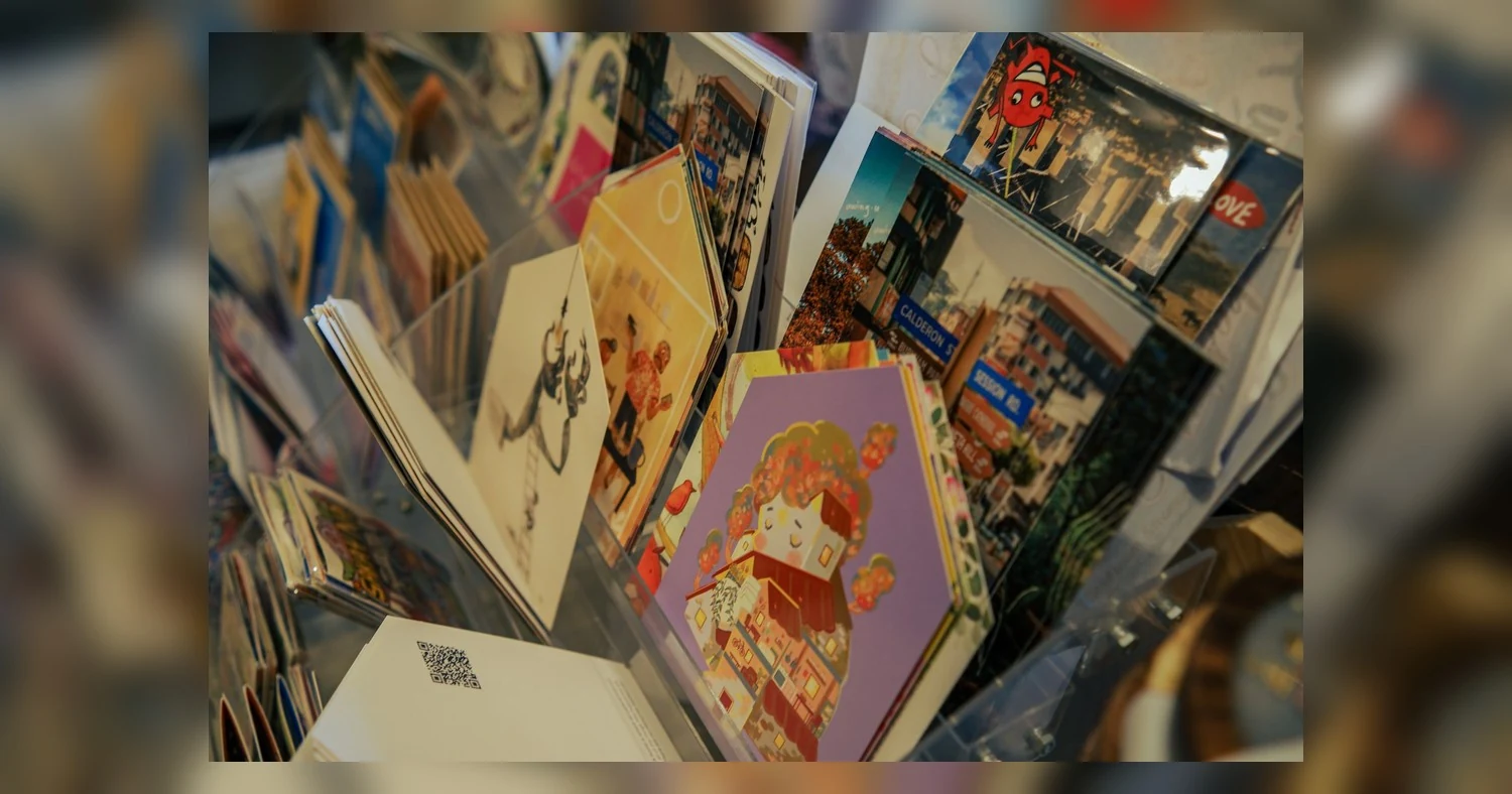 AQ vs UV coating — A colorful assortment of postcards featuring art and scenic views displayed on a rack.