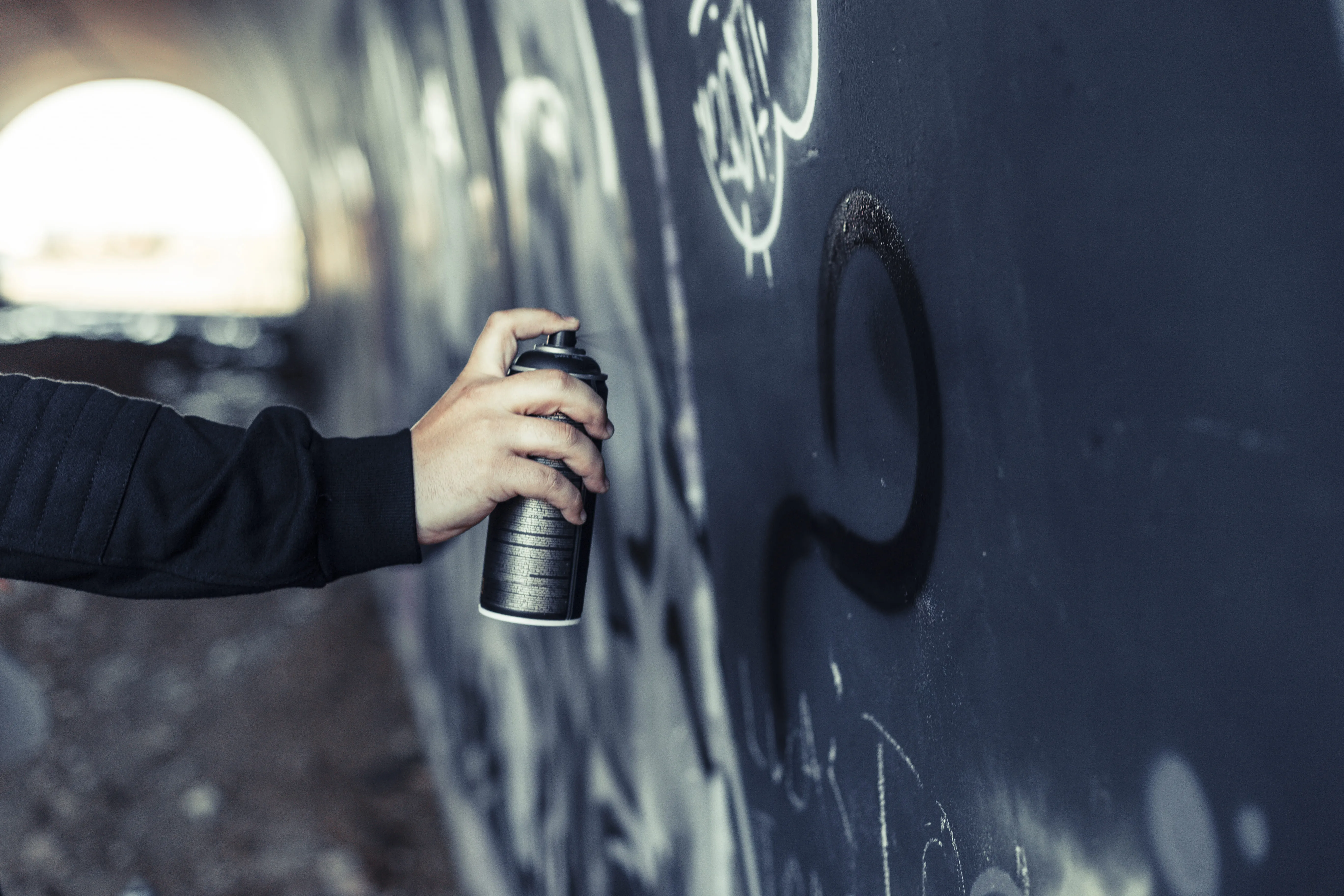 close-up-person-hand-spraying-paint-with-aerosol-can-graffiti-wall